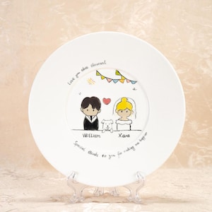 Può includere: Piatto in ceramica bianca con un'illustrazione dipinta a mano di una coppia, un cane e uno striscione con bandiere. Il testo "Love you this thousand" è scritto sopra la coppia. I nomi "William" e "Xara" sono scritti sotto la coppia. Il testo "Special thanks to you for making me happier" è scritto sotto i nomi.