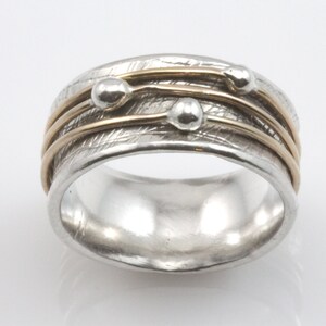 May include: A silver ring with three gold bands and three silver beads. The ring has a textured surface.