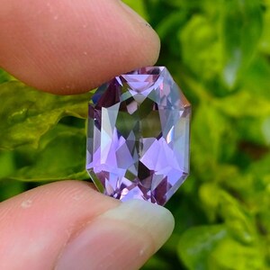 Peut inclure: Une pierre pr&eacute;cieuse d'am&eacute;thyste facet&eacute;e avec une teinte violette. La pierre pr&eacute;cieuse est taill&eacute;e en forme octogonale et a un haut poli.