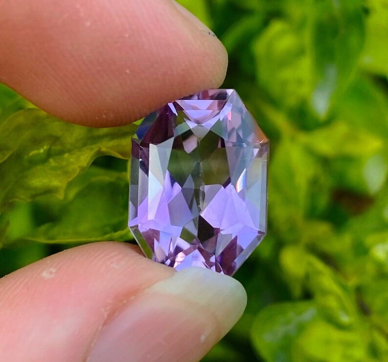 Peut inclure: Une pierre pr&eacute;cieuse d'am&eacute;thyste facet&eacute;e avec une teinte violette. La pierre pr&eacute;cieuse est taill&eacute;e en forme octogonale et a un haut poli.