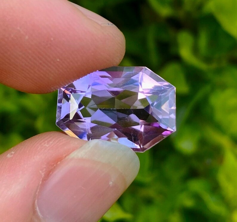 Peut inclure: Une pierre pr&eacute;cieuse d'am&eacute;thyste facet&eacute;e avec une teinte violette. La pierre pr&eacute;cieuse est taill&eacute;e en forme octogonale et a un haut poli.