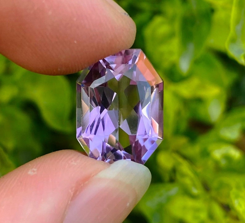 Peut inclure: Une pierre pr&eacute;cieuse d'am&eacute;thyste facet&eacute;e avec une teinte violette. La pierre pr&eacute;cieuse est taill&eacute;e en forme octogonale et a un haut poli.