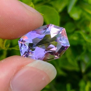 Peut inclure: Une pierre pr&eacute;cieuse d'am&eacute;thyste facet&eacute;e avec une teinte violette et rose. La pierre pr&eacute;cieuse est taill&eacute;e en forme octogonale et a un haut poli.