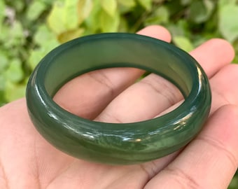 Pode incluir: Um bracelete de jade verde liso e polido. O bracelete é brilhante.
