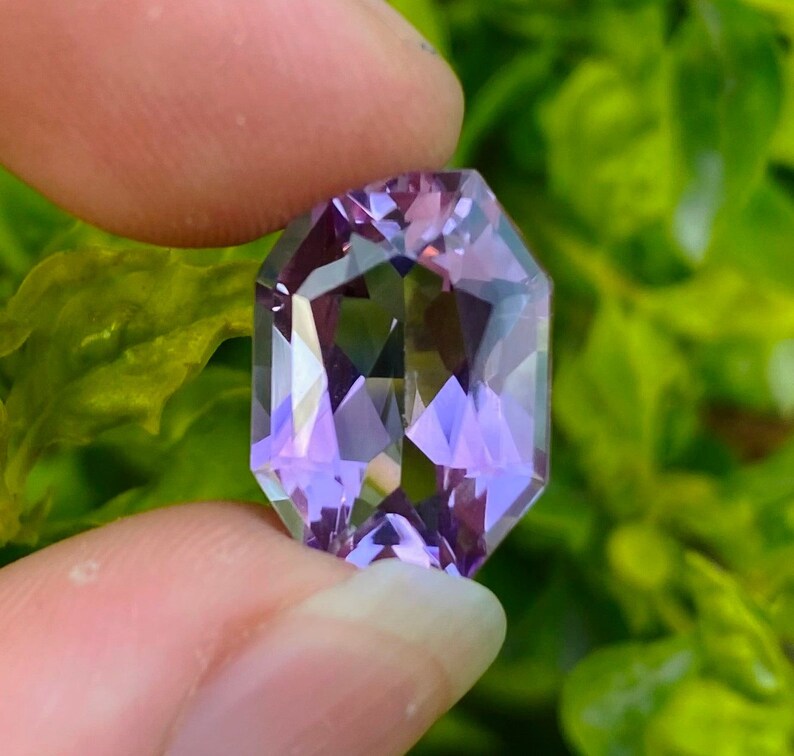 Peut inclure: Une pierre pr&eacute;cieuse d'am&eacute;thyste facet&eacute;e avec une teinte violette. La pierre pr&eacute;cieuse est taill&eacute;e en forme octogonale et pr&eacute;sente un haut niveau de clart&eacute;.