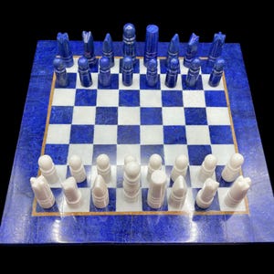 Könnte beinhalten: Ein Schachspiel aus blauem und weißem Marmor mit weißen Figuren auf einem blauen Brett. Das Brett ist aus Lapislazuli und die Figuren aus weißem Marmor.
