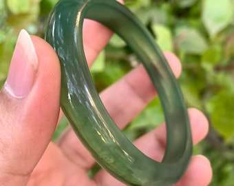 Pode incluir: Um bracelete de jade verde. O bracelete é liso e polido, com um leve brilho.