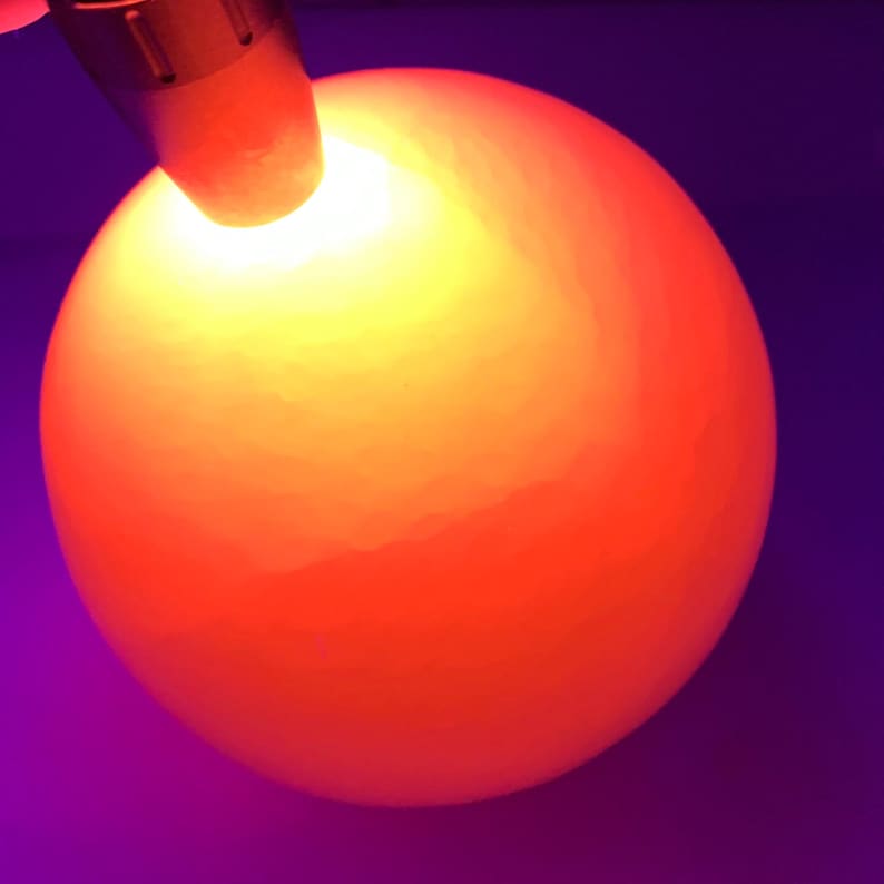 K&ouml;nnte beinhalten: Eine Nahaufnahme eines H&uuml;hnereis, das mit einem hellen Licht durchleuchtet wird. Das Ei wird mit einem warmen orangenen Schein beleuchtet, der das Eigelb und die Luftblase im Inneren sichtbar macht.