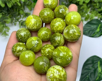 Könnte beinhalten: Eine Sammlung grüner und weißer Serpentin-Kugeln, auch bekannt als grüne Serpentin-Orbs, in verschiedenen Größen. Die Kugeln sind glatt und poliert und haben ein geflecktes Aussehen.