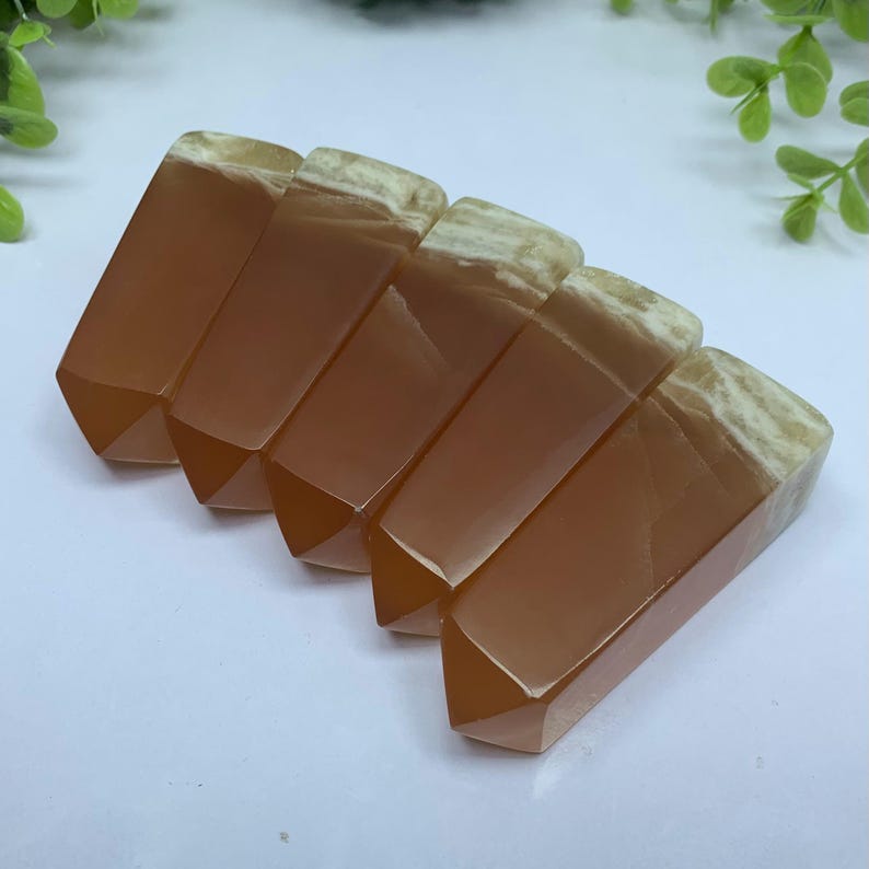 May include: Six orange and white agate crystal points, arranged in a row, with the points facing the same direction.