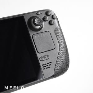 May include: A black handheld gaming device with a textured grip, a circular control pad, and a touchpad labeled "MEELO".