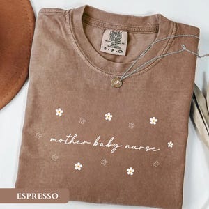 Espresso brown flat lay aesthetic nurse tee displaying an elegant floral mother baby nurse graphic.