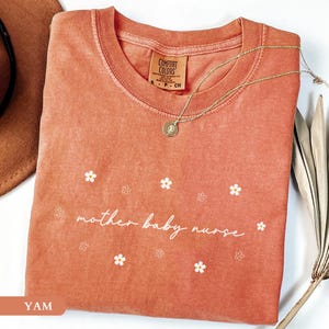 Yam orange cozy maternity nurse shirt flat lay showing a trendy minimalist daisy flower aesthetic.