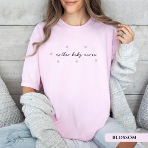 Soft pink blossom aesthetic postpartum nurse shirt worn by a sitting model, featuring an elegant floral design.