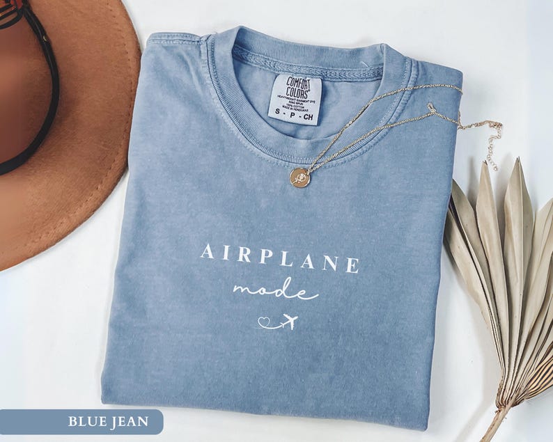 May include: A blue jean t-shirt with the text "Airplane Mode" in white lettering. The shirt has a distressed look and a small airplane graphic.