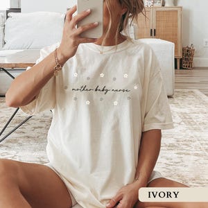 Woman modeling an ivory oversized Comfort Colors tee highlighting the beautiful floral mother baby nurse design, perfect for a work outfit.