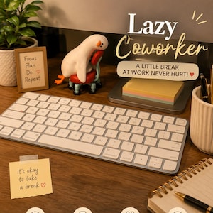 May include: A white goose figurine with an orange beak sitting on a small red office chair. The figurine is placed on a desk with a computer keyboard, a framed sign reading Focus Plan Do Repeat, and a yellow sticky note saying It's okay to take a break.