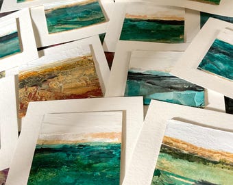 Könnte beinhalten: Eine Sammlung kleiner quadratischer Gemälde auf weißem Papier, die abstrakte Landschaften mit geschichteten Texturen zeigen. Die Kunstwerke weisen horizontale Bänder aus tiefem Blaugrün, Waldgrün, Ocker und weißer Farbe auf.
