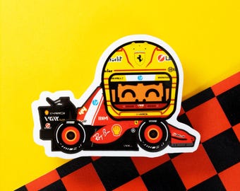 May include: A sticker featuring a cartoon Formula 1 race car with a driver wearing a yellow helmet. The car is red and black with sponsor logos, set against a yellow and checkered background.