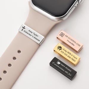 Puede incluir: Una pulsera de alerta médica plateada con el texto "Anna Taylor Alzheimer's disease" está sujeta a una correa de reloj beige. Tres pulseras adicionales en oro rosa, oro y negro muestran información médica y datos de contacto de emergencia.