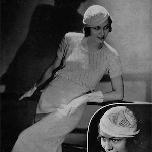 May include: A woman wearing a white knitted sweater and a white knitted hat. The hat has a simple design with a small brim. The sweater has a cable knit pattern. The woman is sitting on a chair and is looking to the side.