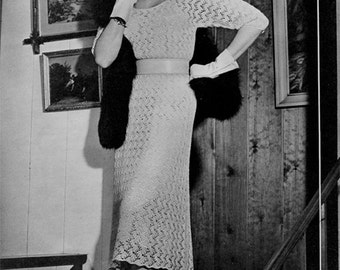 May include: A woman wearing a white crocheted dress with a matching hat and gloves. She is standing on a staircase with a wooden railing.