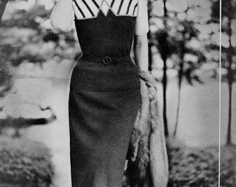 May include: A woman wearing a black and white striped sweater with a black skirt and a fur stole. She is standing in a garden setting.
