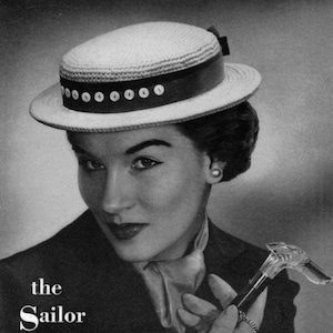 May include: A vintage black and white photograph features a woman wearing a straw boater hat with a dark band and decorative buttons. The hat is styled with a dark ribbon. The text "the Sailor" is at the bottom left.
