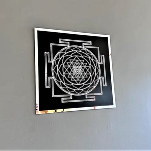 Puede incluir: Un dise&ntilde;o geom&eacute;trico en blanco y negro con un marco plateado. El dise&ntilde;o es un Sri Yantra, un s&iacute;mbolo sagrado en el hinduismo.