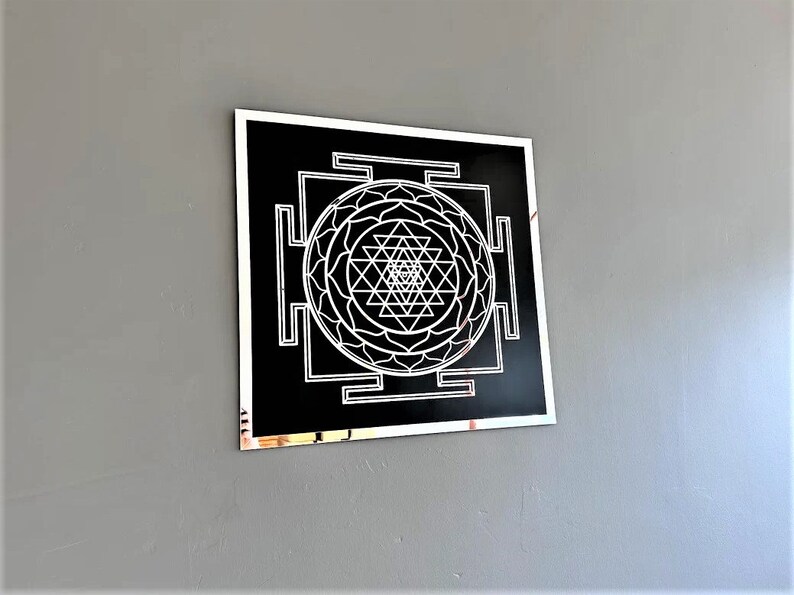 Puede incluir: Un dise&ntilde;o geom&eacute;trico en blanco y negro con un marco plateado. El dise&ntilde;o es un Sri Yantra, un s&iacute;mbolo sagrado en el hinduismo.