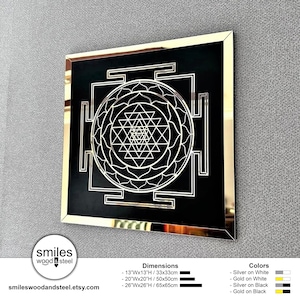 Puede incluir: Un cuadrado negro con un marco dorado, que presenta un dise&ntilde;o blanco de Sri Yantra. La imagen incluye texto para las dimensiones y los colores, incluyendo 13"Wx13"H/33x33cm, 20"Wx20"H/50x50cm, 26"Wx26"H/ 65x65cm, Plata sobre Blanco, Oro sobre Blanco, Plata sobre Negro y Oro sobre Negro.