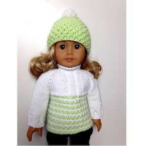 May include: A doll wearing a white and green striped sweater with a green knit hat with a white pom-pom.