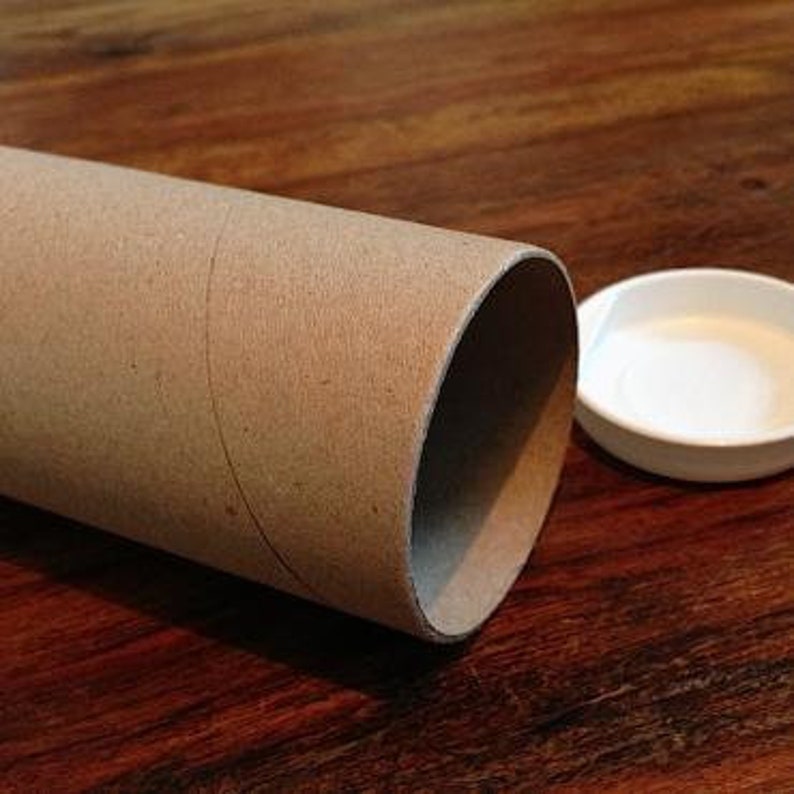 May include: A brown cardboard tube with a white plastic lid. The tube is used for shipping posters or prints.