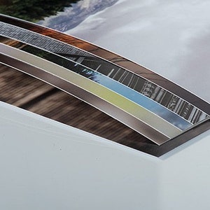 May include: A close-up of a white photo album with a curved edge. The album is open to reveal a series of colorful photographs.