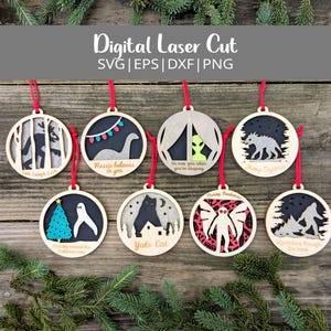 Op de afbeelding: Acht ronde houten kerstversieringen met rode ophanglussen. Elk ornament toont een uniek ontwerp, zoals Bigfoot en Nessie, met teksten als "He sees you when you're sleeping". De ornamenten zijn lasergesneden.
