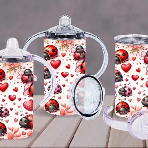 Puede incluir: Un juego de tres vasos y tazas para sorber con temática de mariquitas. Las tazas presentan un fondo blanco con corazones rojos, mariquitas y detalles florales. Una taza tiene pajita y dos tienen asas.