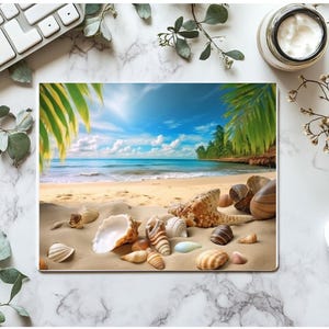 Può includere: Un tappetino per mouse rettangolare con una scena di spiaggia con conchiglie sulla sabbia, palme e cielo blu. Il tappetino è circondato da una tastiera bianca, un mouse bianco ed elementi decorativi.
