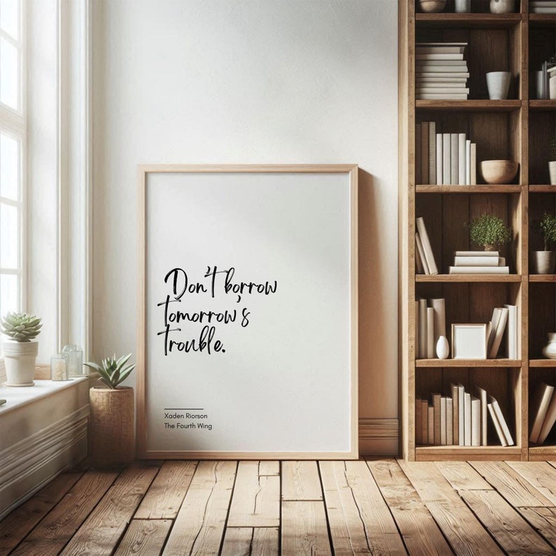 May include: A framed print with a white background and black text that reads "Don't borrow tomorrow's trouble." The text is in a handwritten style. Below the text is the name "Xaden Ronson" and "The Fourth Wing".