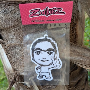 Könnte beinhalten: Ein weißer Auto-Lufterfrischer mit einer Cartoon-Zeichnung einer Person mit einer Augenbraue, die einen Daumen nach oben zeigt. Der Lufterfrischer ist in einer durchsichtigen Plastiktüte verpackt mit einer rosa Kopfzeile, auf der "Zinkiez Air Freshener - Lavender Scented" steht.