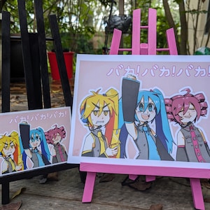 May include: A pink easel with a printed illustration of four anime characters. The characters are wearing colorful outfits and have bright blue, yellow, and pink hair. The text on the easel reads "パカ! パカ! パカ!"