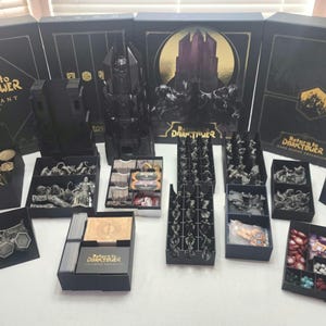 May include: A black and gold board game box set with the title "Return to Darktower Covenant" and multiple black storage boxes filled with game pieces.