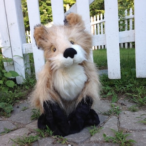 May include: A plush fox toy with brown and white fur, black paws, and a white muzzle. The toy is sitting on a grey stone surface.