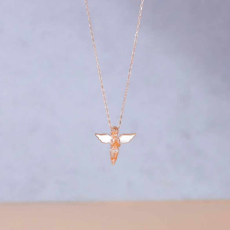 Puede incluir: Un delicado collar de oro con un peque&ntilde;o colgante de &aacute;ngel. El &aacute;ngel es blanco con un cuerpo y alas de oro rosa.