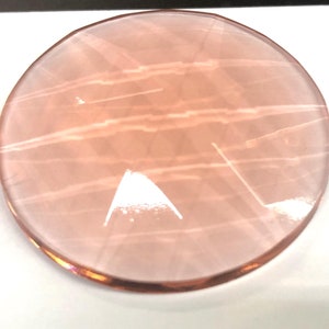 May include: A round, pink, translucent, glass disc with a slightly textured surface.