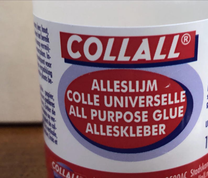 K&ouml;nnte beinhalten: Eine transparente Kunststoffflasche mit Collall Alleskleber. Das Etikett zeigt ein rotes Oval mit dem Text Alleslijm, Colle Universelle, All Purpose Glue und Alleskleber in wei&szlig;er Schrift sowie den Markennamen Collall auf einem roten Balken.