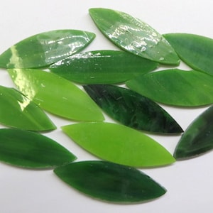 May include: A collection of green glass leaf-shaped mosaic tiles. The tiles are various shades of green, from light to dark.