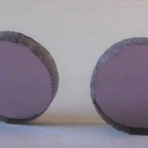 May include: A pair of round, purple, ceramic earrings. The earrings are smooth and have a slightly textured edge.