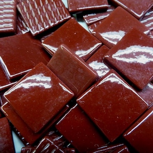 May include: A collection of glossy, square, burgundy-colored tiles. Some tiles have a smooth surface, while others feature a textured pattern. The tiles are arranged in a random, overlapping manner, creating a visually interesting mosaic effect. Ideal for craft projects.