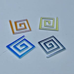 May include: Four square-shaped pieces of clear plastic with a spiral design. The spirals are in different colors: orange, yellow, blue, and black.