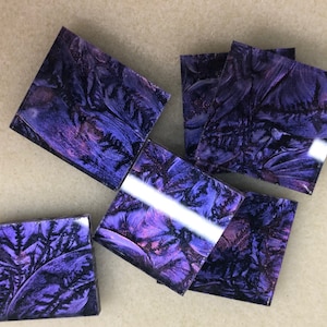 May include: Six square tiles with a purple and pink marbled pattern. The tiles have a glossy finish and a slightly iridescent sheen.